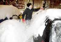 Den här bilisten i Helsingfors putsar exemplariskt bort den snö som fallit på hens bil. Arkivbild.