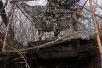 Ukrainska soldater täcker en artilleripjäs för att den ska bli svårare att upptäcka för Rysslands så kallade kamikazedrönare. Bilden togs vid fronten i Bachmut i fredags.