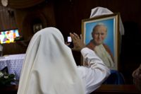 En nunna i Nicaraguas huvudstad Managua tar en bild på ett porträtt av den tidigare påven Johannes Paulus i en katedral 2015.