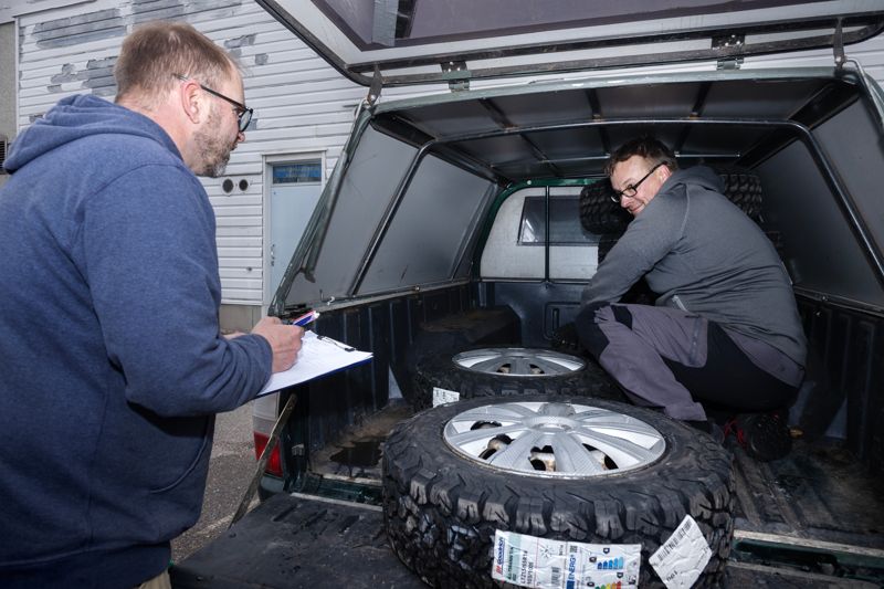 Roope Roine bokför och Mikko Suvinen packar reservdäck i en av terrängbilarna. – De har önskat sig rejäla däck med mönster som passar leriga vägar, för det värsta menföret har just börjat i Ukraina, vägarna är blöta och man kommer inte fram med slitna däck, förklarar Roope Roine.