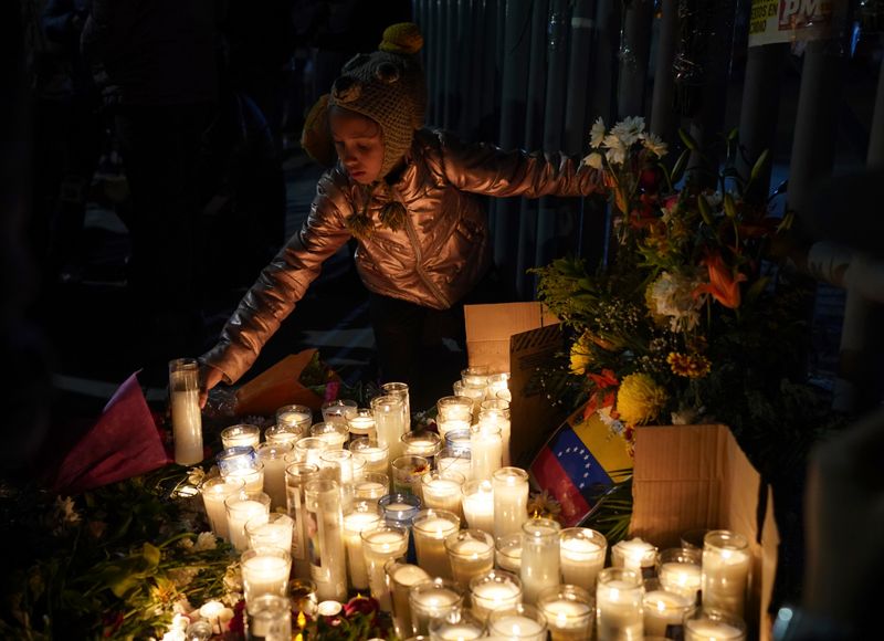 En flicka från Venezuela tänder ett ljus under en vaka för offren i brandkatastrofen som tog minst 38 migranters liv i Mexiko.