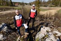 Kalevi Ilonen och Jari Johansson är två av spindlarna i nätet inför Jukola 2023, som ordnas i Borgå i mitten av juni. – Här uppe på kullen finns tv-centret, och härifrån har man den bästa utsikten över tävlingscentret, säger Jari Ilola. Till vänster bakom dem kommer en by av vindskydd att byggas upp, där orienterarna kan byta om efter sitt lopp.