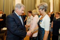 Här har Ekenäsmamman Regina Koschinski fått sin morsdagsmedalj och skakar hand med president Sauli Niinistö.
