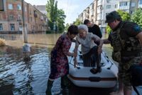 En äldre kvinna kliver ur en gummibåt i regionen Cherson i södra Ukraina.