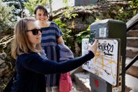 Nadina Vihinen provskannar en av vandringens QR-koder. Koden leder till ett uppslag om Näse sten, ett uppslag som finns i Filippa Hellas (i bakgrunden) bok ABC i Borgå.