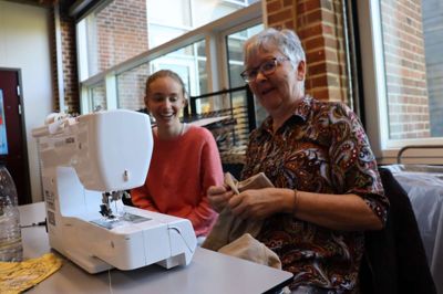 Lene Andersen fra repaircafeen i Brande hjælper Karoline Sandberg med at få forkortet et par bukser, så de får et nyt liv og kan bruges igen.