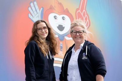 Matilde Brixen og Pia Trab Worm har det overordnede ansvar for 500 frivillige under VM i Ishockey. Her er de fotograferet foran et billede af VM-maskotten Beaty, der er både »livlig, adræt og hopper rundt og spreder energi til alle omkring sig - altid med høj puls.«