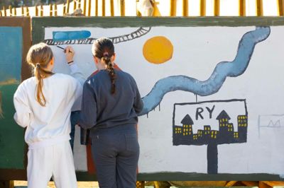 Elever fra Mølleskolen var nogle af de første til at male på de mange træplader, som har omkranset byggepladsen ved Ry Hallerne. Nu kan man købe de mange malerier - pengene går til et nyt kunstprojekt.