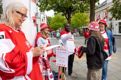 Under VM i ishockey har der været godt gang i salget af Mødrehjælpens hæklede rød-hvide bøllehatte. Her er Charlotte Andersen (t.v.) og Marianne Nickelsen ved at sælge et par hatte til nogle begejstrede fans.