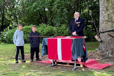 Formand for Dannebrogs-Samfundets Skive-afdeling Preben Sloht gør klar til at slå det første søm i fanen for kongen, mens Andreas og Albert fra FDF Stoholm ser til. Privatfoto