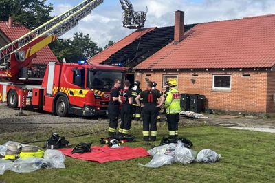 Indsatsleder Kasper Mejer Andersen, med gul hjelm og jakke, er her i dialog med en gruppe af de brandfolk, der blev kaldt til Asbækhedevej 6 mellem Aulum og Vildbjerg mandag morgen.