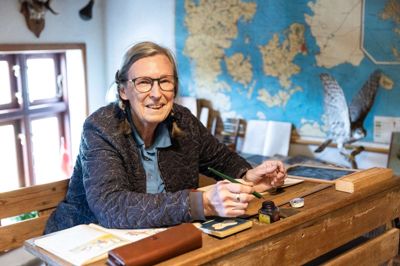 Hos Den Gamle Købmandsgård i Uhre findes der også et gammeldags skolehjørne. Her har en af stedets frivillige, Lise Lotte Møller Pedersen, sat sig på skolebænken.