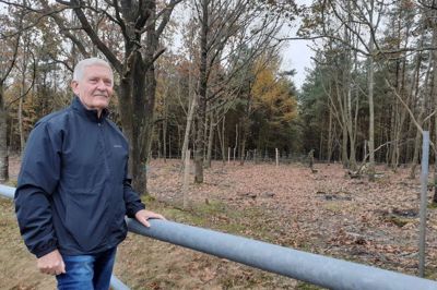 Knud Nielsen ved en af de nu afspærrede stier ind i skoven på Nybro Møllevej. Bommen er lukket, to rækker hegn sat op og nye træer er plantet ved stien ind mellem træerne.