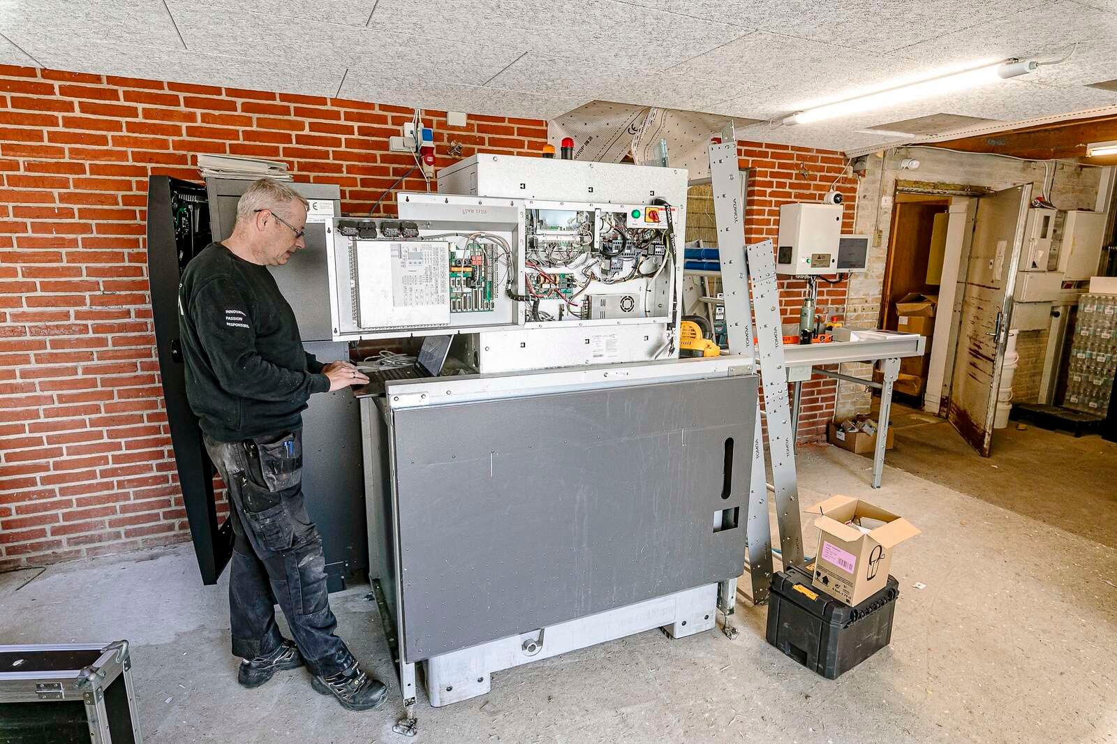 Montører fra firmaet Tomra er i gang med at installere Morten Pedersens nye flaskeautomat til 200.000 kroner.