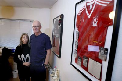 June og Jan Hede på klinikken i Sjællandsgade, hvor fodboldtrøjer fra både Liverpool FC og FC Midtjylland pryder væggen. Han har været klublæge i FCM i 20 år - men Liverpool-fan meget længere end det. Og så er han gift med June, der er født og opvokset i Liverpool. Foto: Flemming Hansen