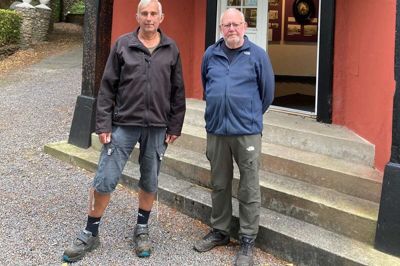 Foran den rødlige bygning med de sorte bjælker ses Hans Nørgaard og Jens Peder Wolff fra bestyrelsen for Haderup Lokalhistorisk Museumsforening.