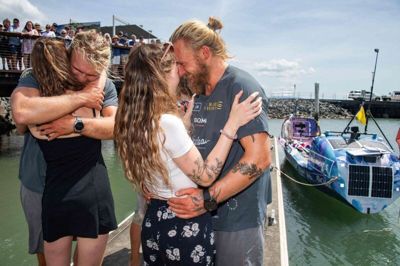 Lachlan og Jamie MacLean i omfavnelse med deres kære ved ankomst til Cairns i Australien efter en tur på 14.500 kilometer.