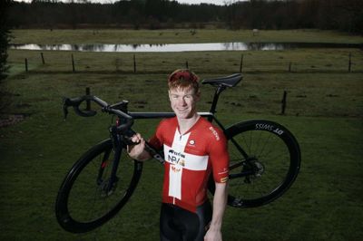 Til ære for fotografen har Henrik Breiner Pedersen taget sin cykel med om i baghaven til familiens hus, der ligger et par kilometer uden for Sdr. Felding - på hovedvejen mod Skjern. Dannebrogstrøjen vandt han i juni, da han blev dansk mester på landevej for U19-rytterne. Foto: Henrik Ole Jensen