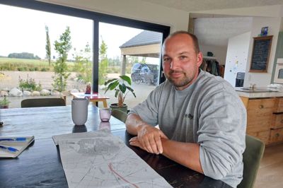 Jan Jonassen med kortet over den nye 2+1-vej mellem Herning og Ringkøbing, der vil løbe lige ude på marken bag ham. Jan Jonassen føler sig kørt over af myndighederne.