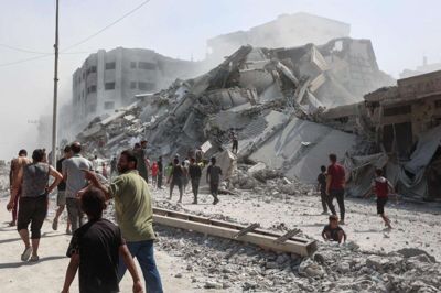 Palæstinensere samles omkring ruinerne af højhuset al-Ghafari i Gaza By. Bygningen blev ødelagt i et israelsk angreb mandag. Israels militær har varslet en fortsat offensiv i Gazastribens største by og har opfordret de hundredtusindvis af palæstinensere i byen til at forlade den.