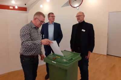 Valgstyrer-formand og 1. viceborgmester i Ringkøbing-Skjern Kommune, Søren Elbæk (A) smider stemmesedlen i boksen, mens borgmester Hans Østergaard (V) og valgtilforordnede Tage Møller kigger på. Foto: Mette Christensen