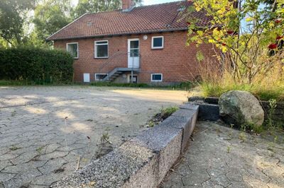 Forrest en af de barrikader, bruger af det kreative værksted i Ellemosen i Ry selv har bygget for at holde regnvand ude af deres værksted. Bagerst den tidligere Klub Rust, hvor værkstedet midlertidigt kan få plads. Foto: Sonne