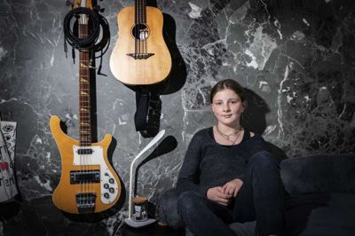 Marie Nielsen på sit værelse, hvor hendes fars gamle bas hænger ved siden af hendes egen akustiske. Foto: Marin ballund