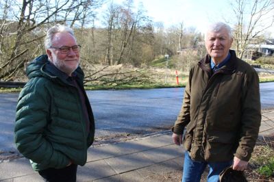 Anders Hartvig og Lars Daugaard er klar til at arbejde for 170 meter ny sti ved Hørup Mølle og det gamle Dommerkontor i Kjellerup. På billedet ses overgangen for den kommende sti ved Kirkebakken - markeret med orange kegle i baggrunden. Foto: Rasmus Viuff