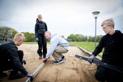 Lærer René Andersen sammen med nogle af de elever, der er en del af den erhvervsrettede linje på Thorning Skole. På billedet lægges der fliser på springgraven ved boldbanerne i Thorning. Foto: Jakob Stigsen Andersen