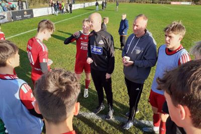 Idrætslærerne Mads Hamann og i den grå trøje Klaus Jepsen giver gode råd i pausen. Drengene på Sunds Skoles fodboldhold får at vide, at de skal være rollemodeller for de andre elever på solen. Opfører de sig ikke ordentligt i skolen, bliver de sat af holdet.