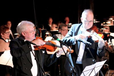 Jan G. Østergaard, som her ses i færd med at spille violin med en mælkeskummer ved musikskolens nytårskoncert i januar, skal både i aktion som dirigent og sangsolist ved tirsdagens forårskoncert