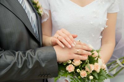 Hands of a newly-married couple. Tenderness of the groom and the bride above wedding a bouquet