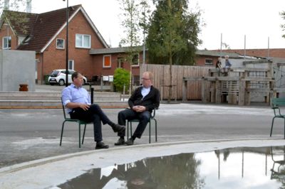Grønne stole uden fast placering og til fri afbenyttelse står omkring mødestedet, der som et andet gadekær skal være det naturlige omdrejningspunkt i det nye Bording. Henrik Engedal og Ib Lauritsen glæder sig over det synlige resultat af den langstrækte proces, der i den grad involverede borgere foto Laila Kempel