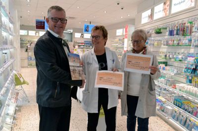 Kurt B. Jespersen fra Hjerteforeningen og Inger Kristensen fra Diabetesforeningen (t.h.) får her det synlige resultat af overskuddet fra salget af jubilæumsbogen for Ikast Apotek af apoteker Karen Marie Østergaard. ?foto: Laila Kempel