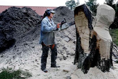 Susanne Ahrenkiel knoklede næsten seks timer i streg. Den ene time brugte hun på at »grave« to store sten ud, som kunstneren og motorsaven absolut ikke brød sig om. Oprindeligt var det planen, at kunstneren skulle have arbejdet på træstammen ved siden af. Men den fandt hun for lille, og gik i stedet i gang med den større og mere udfordrende stamme. Foto: Henrik Ole Jensen