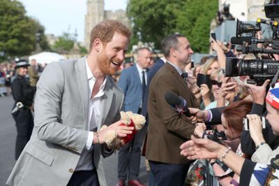 Reuters/Pool. Prins Harry tager imod en lille rødklædt bamse, mens han fredag aften hilser på royale fans ved Windsor Castle.