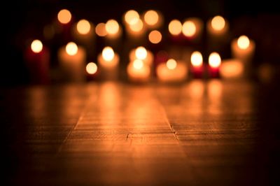 Defocused lit candles burning in the Church, spirituality and religion concept