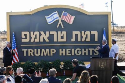 Israels premierminister, Benjamin Netanyahu (th) iklædt jakkesæt, og USA's Israel-ambassadør, David Friedman (tv), klapper, da et stort skilt afsløres på Golan-højderne med navnet på en ny, lille bosættelse.