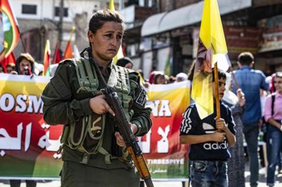En kurdisk politikvinde holder vagt under en demonstration i byen al-Qahtaniyah i det nordøstlige Syrien mandag. Kurderne frygter en tyrkisk offensiv efter USA's melding om, at amerikanske soldater ikke kommer til at stå i vejen for det.