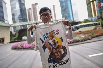 En fan fremviser en t-shirt med basketspilleren LeBron James uden for et hotel i Shanghai, hvor han håber på at få et glimt af NBA-stjerner inden en opvisningskamp mellem Brooklyn Nets og The Los Angeles Lakers.