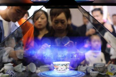 Besøgende tager billeder af et hologram, der viser en kinesisk tekop. Den er projiceret ind i en glasmontre på en teknologiudstilling i Nanchang i Kina i 2019. Det er en sådan teknolog,i som Kina ønsker, at man skal kunne beherske på et nyt internet.