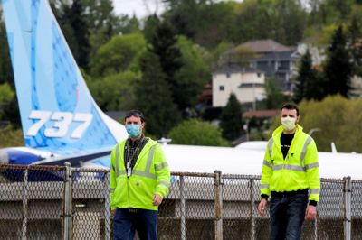 Boeing-ansatte med masker for mund og næse ses her ved Boeings fabrik i Renton i den amerikanske delstat Washington. Boeing beskæftiger 160.000 ansatte over hele verden, men antallet af medarbejdere skal skæres ned nu efter to kvartaler med tab.