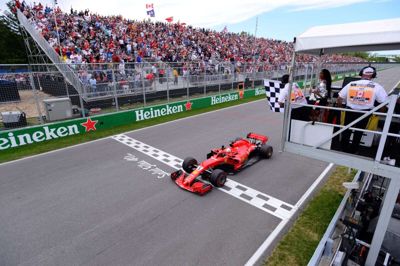 Ferraris Sebastian Vettel passerer målstregen foran en masse fans i et grandprix i en tidligere sæson. Det er endnu usikkert, om nogle af årets Formel 1-grandprixer kan gennemføres med tilskuere. (Arkivfoto)