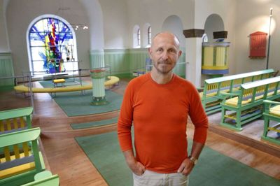 Hvert år kommer 20-25 busser med besøgende fra nær og fjern for at se den farverige Uhre Kirke, så sognepræst Arne Holst-Larsen stiller ofte op som »turistguide« i landsbykirken, som blev opført - i en mere brunlig udgave - for 100 år siden. Foto: Flemming Hansen