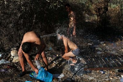Mænd tager et bad i den nedbrændte Moria-lejr på øen Lesbos i Grækenland.