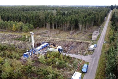 De to seneste istider kan aflæses i landskabet i Gludsted Plantage, hvor blandt andet morænebakken Isenbjerg er et efterladenskab fra den næstsidste istid for over 100.000 år siden. Men det er ungt i forhold til de depoter af rent grundvand, som ligger endnu længere nede. I jagten på at fremtidssikre drikkevand til forbrugerne, har Ikast Vandforsyning A.m.b.a. lavet fire nye boringer, hvoraf nogle er nået ned til lag i undergrunden, der er skabt for op mod 24 millioner år siden. På dette dronefoto ses brøndborefirmaet A. Højfeldt A/S fra Herning i færd med »dybdeborende« arbejde ved en af de fire kildepladser i plantagen. Foto: Tom Laursen