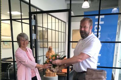 Bodil Bundgaard har officielt sagt farvel til sin arbejdsplads gennem de sidste 48 år . Handelsbankens direktør Kenneth Kristiansen - den syvende i Bodil Bundgårds arbejdstid - takkede hende for indsatsen med blandt andet en buket blomster. Foto: Privat
