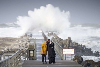 Natten til lørdag kan der komme vindstød af stormstyrke ved de nordvestvendte kyster. Her ses to turister, der tager en selfie i Nørre Vorupør, mens stormende kuling med vindstød af stormstyrke ramte Nordjylland i januar. (Arkivfoto).