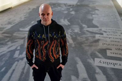 Kunstneren Peter Brandt mødte op i Ikast for at forklare sin kunstneriske praksis omkring den aktuelle udstilling. Her ses han midt i værket »Resistance and Vulnerability«, der er udført i samarbejde med grafisk designer Andreas Lind Johansen og Egetæpper. Foto: Kunstpakhuset