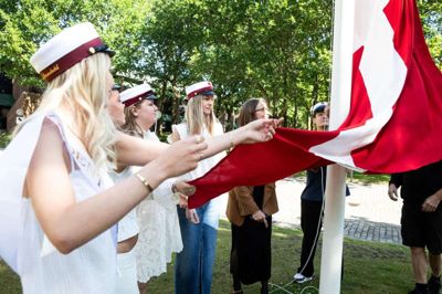 Årets første studenter fra Ikast-Brande Gymnasium, Dicte Grundal (t.v) Maja Hvilshøj Liin, Maria Stræde Palmelund, Karoline Hedegaard Horshauge, rektor Marianna Dose Hvid, og Marcus Nielsen kunne i fællesskab løse den traditionelle og glade opgave med at få det danske rød-hvide flag sendt til tops efter veloverstået eksamen. Foto: Malene Korsgaard